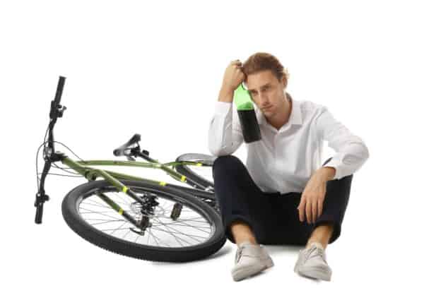 A man holding a bottle of wine has likely been biking under the influence, a crime under California Vehicle code section 21200.5 (VC)