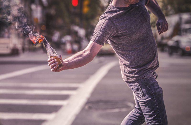 A man preparing to throw a molotov cocktail used to illustrate looting laws in California