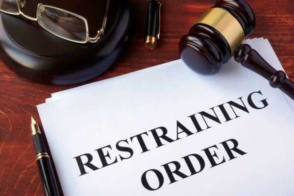 Paper saying "restraining order" with a gavel and glasses 