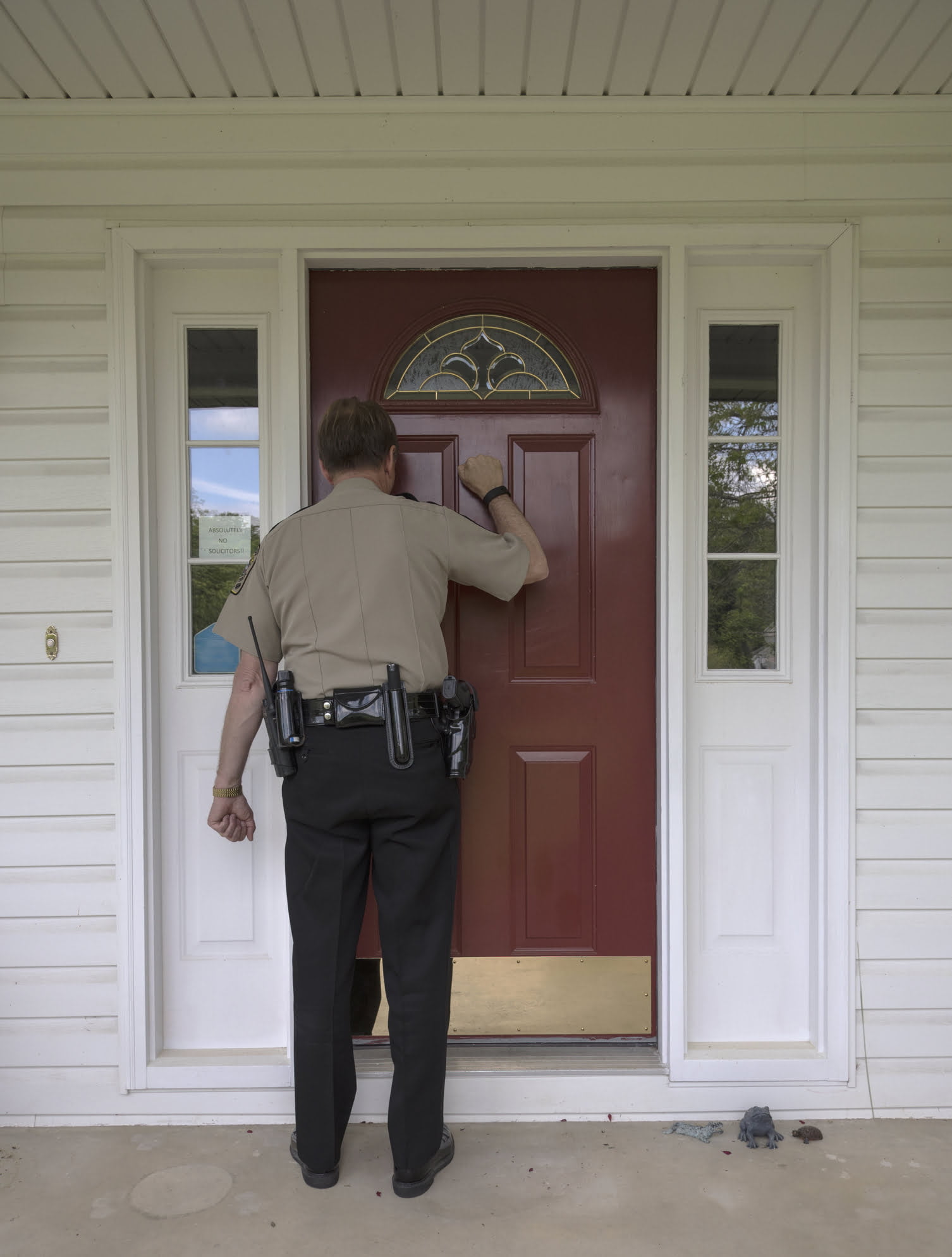 A man impersonating a peace officer knocks on a door.