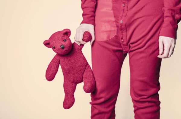Abogado por Cargos de Pornografía Infantil 2 Un joven en pijama sosteniendo un osito de peluche.