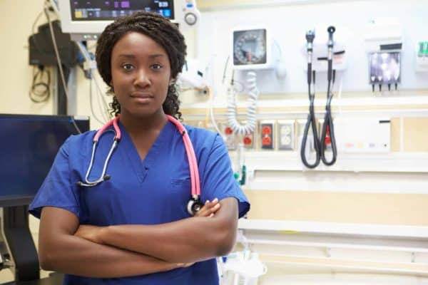 A female doctor stands with her arms crossed over her chest.